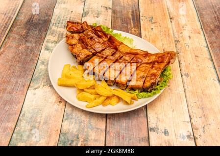 Schweineribs in Sauce mariniert und auf dem Grill mit hausgemachten Pommes auf dem Holztisch gekocht Stockfoto