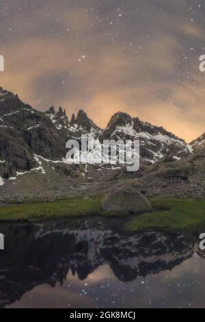 Malerische Landschaft von hohen felsigen Bergen mit Schnee bedeckt, die sich in ruhigem Wasser des Flusses unter sternenklaren Nachthimmel spiegeln Stockfoto