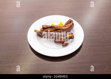 Zwei geröstete Rippen auf weißem Teller und dunklem Tisch Stockfoto