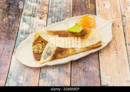 Dulce de leche crepe mit Biskuitboden, gehackten Mandeln und Scheiben von grünem Apfel Stockfoto