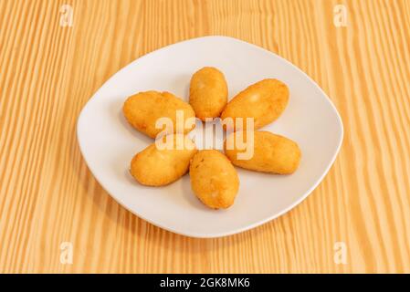 Tapa spanischer Kroketten, gefüllt mit Béchamel und iberischem Schinken, paniert mit Brot auf einem weißen Teller Stockfoto