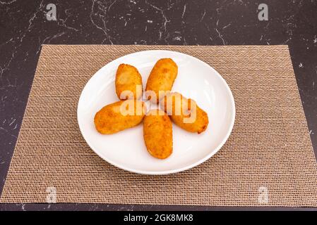 Ration von mit Brot und Ei geschlagene Kroketten, gefüllt mit Béchamel und serrano-Schinken auf einer Plastiktischdecke Stockfoto