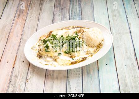 Mexikanisches Tablett mit grünen Enchiladas mit rohem weißem Reis, Petersilie, Koriander und Zwiebeln Stockfoto