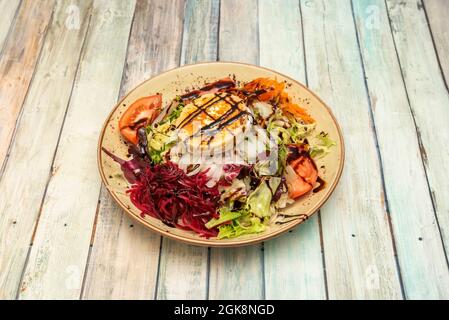 Ziegenkäse-Salat mit Eisbergsalat, frischen Tomaten, Karotten und geriebenen Rüben, rohen weißen Zwiebeln und Balsamico-Essig mit Olivenöl Stockfoto