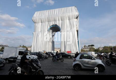 Paris, Frankreich. September 2021. Pendler fahren am Montag, den 30. September 2021, um den Arc de Triomphe, der in silberblauem Stoff gewickelt wird. Das Wahrzeichen ist mit 25,000 Quadratmetern Material bedeckt und erfüllt posthum einen 60-jährigen Traum für den Künstler Christo. Foto von Eco Clement/UPI Credit: UPI/Alamy Live News Stockfoto