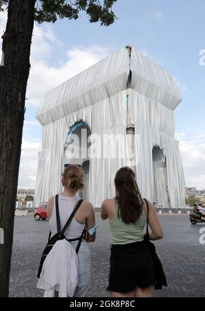 Paris, Frankreich. September 2021. Junge Damen schauen sich den Arc de Triomphe an, der am Montag, den 30. September 2021, in Paris, Frankreich, in silberblaues Gewebe gewickelt wird. Das Wahrzeichen ist mit 25,000 Quadratmetern Material bedeckt und erfüllt posthum einen 60-jährigen Traum für den Künstler Christo. Foto von Eco Clement/UPI Credit: UPI/Alamy Live News Stockfoto