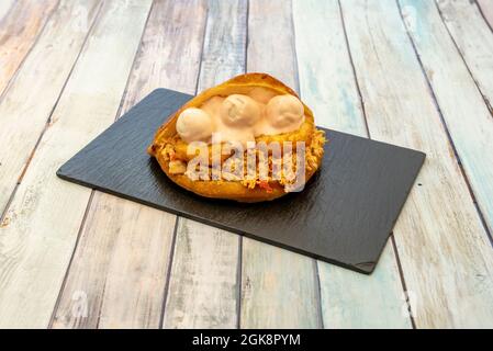 Arepa von geschreddertem Fleisch mit Stücken von tequeños und Sauce auf schwarzem Schiefertisch Stockfoto