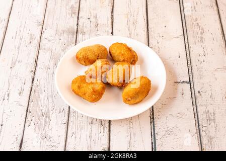 Typisch spanische Tapa aus Kroketten, gefüllt mit Béchamel und iberischen Schinkentacos auf einem weißen Teller Stockfoto