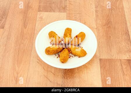 Frisch zubereitete panierte Kroketten, gewürzt mit Stücken gebratenen serrano-Schinkens auf einem Holztisch Stockfoto