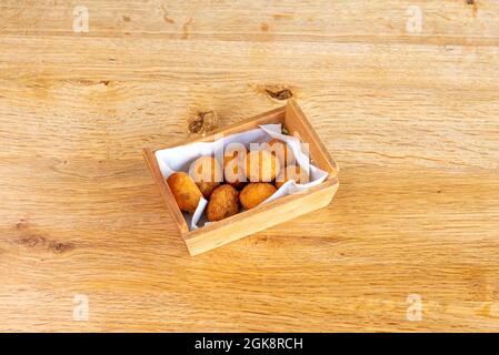 Spanische Tapa von iberischen Schinkenkroketten in Holzbehälter und auf Holztisch in hellem Eichenholz Ton Stockfoto