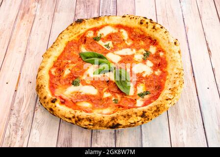Kleine Pizza mit superfeinem Mehlteig mit viel scharfem Chorizo und Basilikumstücken darauf. Stockfoto