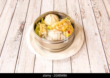 Dim Sum und verschiedene gedämpfte Gyozas, die von einem chinesischen Koch in einer Metallschüssel zubereitet werden Stockfoto