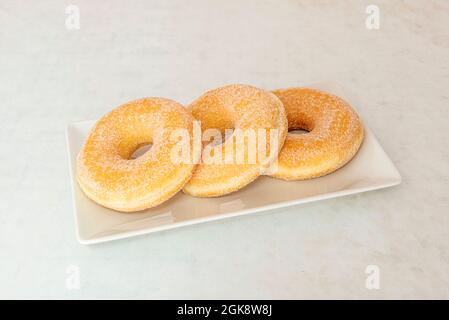 Tablett mit drei Zuckerdonuts mit Löchern auf einem weißen Tablett Stockfoto