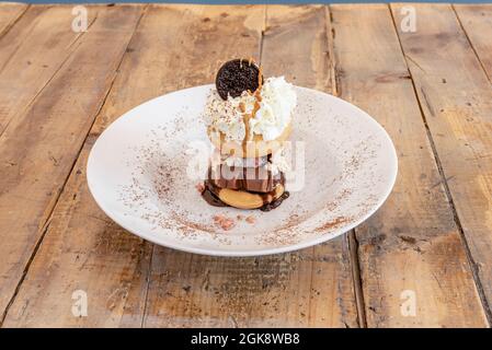 Köstliches Dessert von Donuts Liebhaber mit Schokolade Bar, Schokoladenkeksen, Schokoladensirup, pulverförmige Schokolade, gesprenkelte Creme und knackige Schokolade Stockfoto