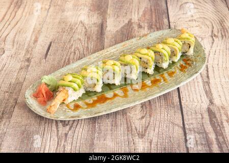 Uramaki-Drachenrolle mit gebratenen, zerschlagten Garnelen, Avocado-Scheiben und Wasabi mit Ginseng Stockfoto