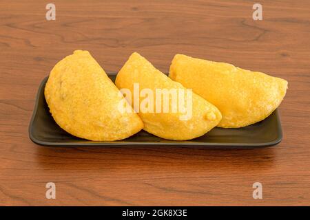 Portion mit drei kolumbianischen Maismehl Empanadas auf Holztisch Stockfoto