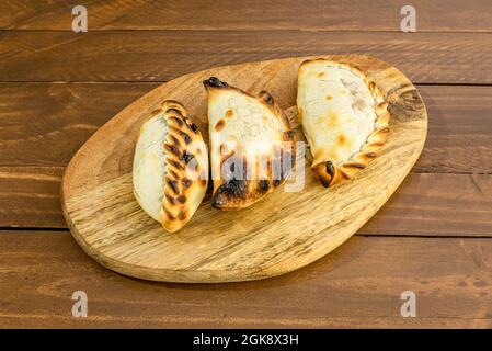Argentinische Empanadas, gefüllt mit gut gekochtem, gebratenem Fleisch auf Holzbrett Stockfoto