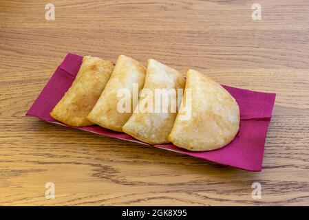 Chilenische Fleischempanadas auf rotem Klotter und Holztisch Stockfoto
