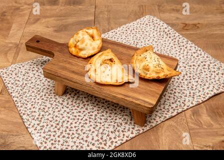 Empanadas von verschiedenen Geschmacksrichtungen mit argentinischen Rezepten auf Holzbrett mit Beinen gemacht Stockfoto