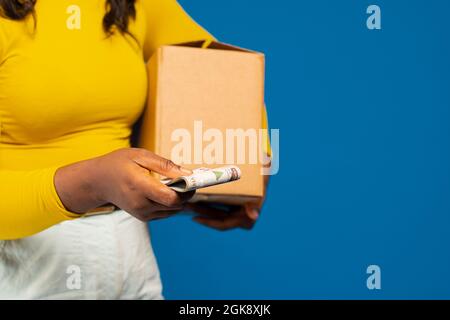 afrikanische Frau hält einen Kasten mit etwas Bargeld, Zahlung auf Lieferung Konzept Stockfoto