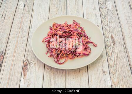 Salat aus purpurfarbenem Kohl mit Mayonnaise, Essig und gehacktem Schnittlauch auf einem weißen Tisch. Stockfoto