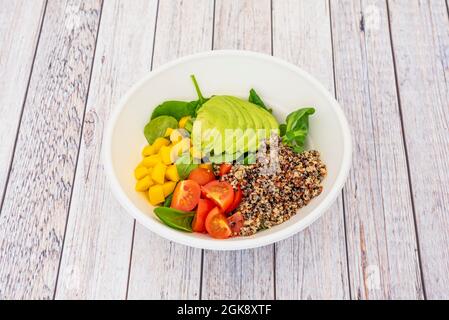 Gemüsesalat mit gekochten weißen und roten Quinoa. Gehackte Kirschtomaten, mexikanische reife Avocado, asiatische gehackte Mango und spanischer Lammsalat. Stockfoto