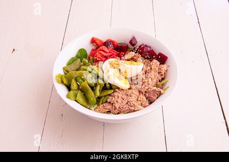 Nordischer Bonito-Salat mit gekochten grünen Bohnen, hart gekochten Eiern, Sesamsamen, Spinatsprossen, gerösteten Piquillo-Paprika und gehackten Rüben Stockfoto