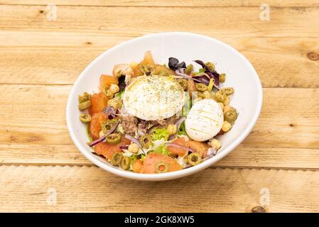 Toller mediterraner Salat mit vielen Gewürzen. Laminierte gekochte Eier, Thunfisch aus der Dose, Ziegenkäse, Stücke von grünen Oliven, gekochte Kichererbsen, gehackte t Stockfoto