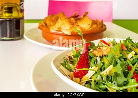 Rucola-Salat mit Parmesankäse mit Walnüssen und Erdbeeren im veganen Restaurant Stockfoto