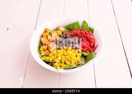 Gerösteter Piquillo-Pfeffer-Salat in Streifen, Bulk-Mais, Surimi Tacos, schwarze Olivenscheiben und Spinatsprossen Basis. Stockfoto