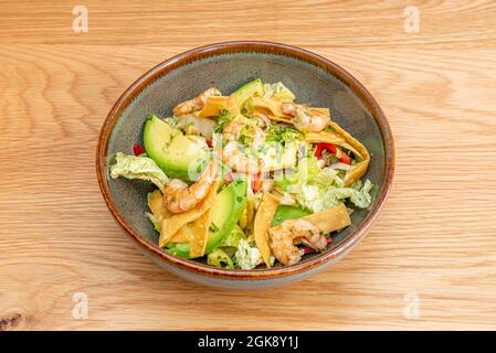 Toller Shrimp-Salat, Avocado, Streifen von Maischips, Eisbergsalat, viel Petersilie und Öl in einer grauen Schüssel mit braunem Rand. Stockfoto