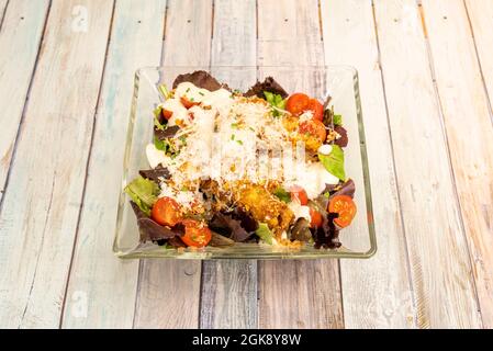 Caesar-Salat mit frischen Zutaten, geteilten Kirschtomaten und viel geriebenem Käse in einer Glasschüssel Stockfoto