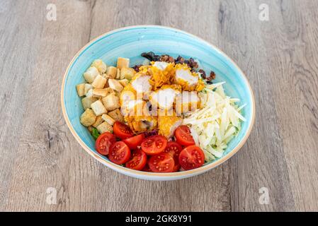 Cesar-Salat mit getrennten Zutaten in einer wunderschönen himmelblauen Schale auf einem grauen Holztisch Stockfoto