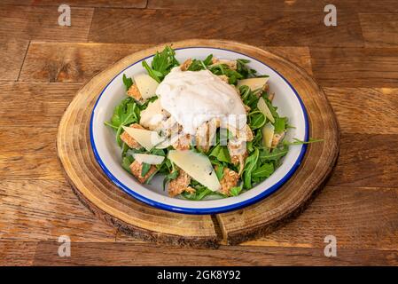 Caesar-Salat mit frischen Zutaten, Croutons, Rucola und Manchego-Käsescheiben auf Holzscheibenholz Stockfoto