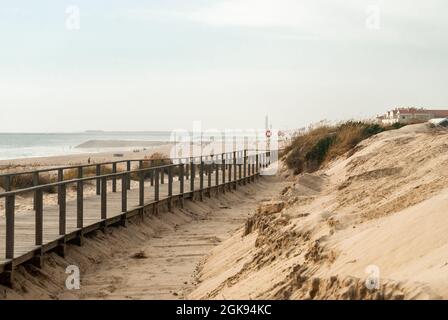 Dünen am Strand mit einem Holzweg entlang der nebligen Küste - Costa Nova, Portugal Stockfoto