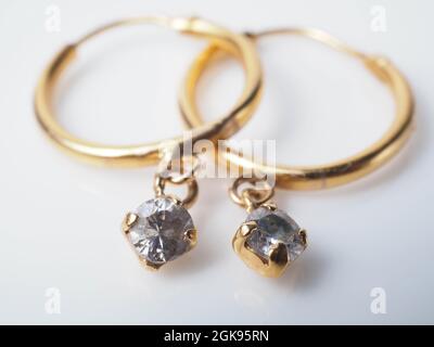Nahaufnahme eines Paares goldener Ohrringe mit Diamanten. Nehmen Sie auf einem weißen, isolierten Hintergrund auf Stockfoto