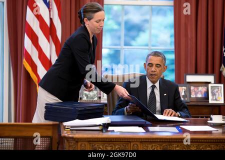 Präsident Barack Obama, unterstützt von der Stabssekretärin Joani Walsh, unterzeichnet Gesetzesvorlagen im Oval Office, 8. August 2014. (Offizielles Foto des Weißen Hauses von Pete Souza) Dieses offizielle Foto des Weißen Hauses wird nur zur Veröffentlichung durch Nachrichtenorganisationen und/oder zum persönlichen Druck durch die Betreffzeile(en) des Fotos zur Verfügung gestellt. Das Foto darf in keiner Weise manipuliert werden und darf nicht in kommerziellen oder politischen Materialien, Anzeigen, E-Mails, Produkten oder Werbeaktionen verwendet werden, die in irgendeiner Weise die Zustimmung oder Billigung des Präsidenten, der ersten Familie oder des Weißen Hauses nahelege. Stockfoto