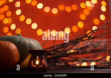 Zweige, Kerze und Halloween Kürbisse auf orangefarbenem Hintergrund mit Bokeh. Speicherplatz kopieren. Stockfoto