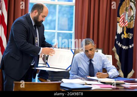 Präsident Barack Obama, unterstützt vom stellvertretenden Stabssekretär Ted Chiodo, unterzeichnet Gesetzesvorlagen im Oval Office, 26. September 2014. (Offizielles Foto des Weißen Hauses von Pete Souza) Dieses offizielle Foto des Weißen Hauses wird nur zur Veröffentlichung durch Nachrichtenorganisationen und/oder zum persönlichen Druck durch die Betreffzeile(en) des Fotos zur Verfügung gestellt. Das Foto darf in keiner Weise manipuliert werden und darf nicht in kommerziellen oder politischen Materialien, Anzeigen, E-Mails, Produkten oder Werbeaktionen verwendet werden, die in irgendeiner Weise die Zustimmung oder Billigung des Präsidenten, der ersten Familie oder des Weißen Hauses nahelege. Stockfoto