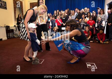 First Lady Michelle Obama erreicht ein Kind während eines Besuchs mit Kindern aus Children's Miracle Network Hospitals im Eisenhower Executive Office Building des Weißen Hauses, 10. November 2014. (Offizielles Foto des Weißen Hauses von Lawrence Jackson) Dieses offizielle Foto des Weißen Hauses wird nur zur Veröffentlichung durch Nachrichtenorganisationen und/oder zum persönlichen Druck durch die Betreffenden des Fotos zur Verfügung gestellt. Das Foto darf in keiner Weise manipuliert werden und darf nicht in kommerziellen oder politischen Materialien, Werbung, E-Mails, Produkten oder Werbeaktionen verwendet werden, die in irgendeiner Weise nahelegt Stockfoto