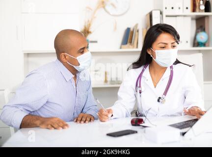 Arzt schreibt Rezept an Patienten in der Klinik Stockfoto