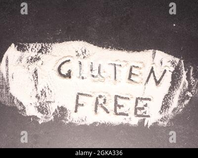 Glutenfrei in Mehl auf einem dunklen Stein Küchentisch geschrieben, gesundes Lebensmittelkonzept Stockfoto