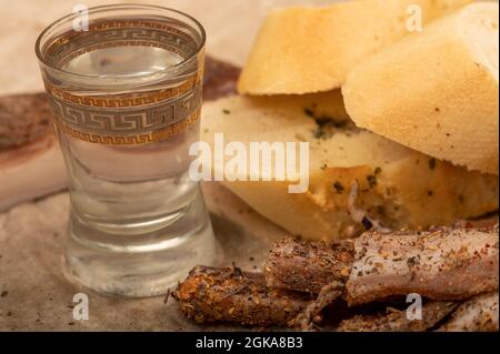 Hausgemachter Speck in Scheiben mit Pfeffer, Brotscheiben und einem Glas hausgemachten Moonshine, Nahaufnahme, selektiver Fokus Stockfoto