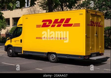 Seitenansicht von hinten links eines DHL-Transporters, der am Straßenrand steht Stockfoto