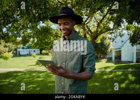 Gemischter Rassenbauer, der im Freien steht und auf einem digitalen Tablet tippt Stockfoto