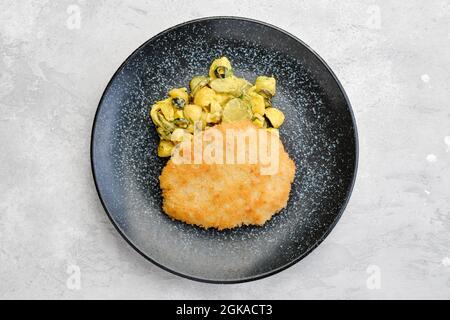 Ansicht von oben auf Schweineschnitzel mit Kartoffel und eingelegter Gurke in Senfsauce Stockfoto