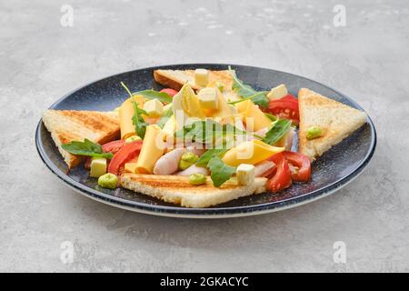 Dreieckige Stücke von Toast, Schinken, gekochtem Ei, Cheddar und Tomaten Stockfoto