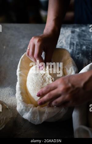 Die Bäckerin formt Brot und legt einen Korb Stockfoto