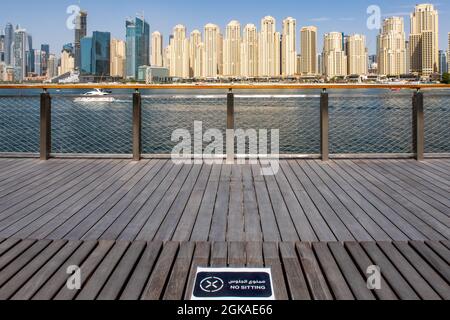 Dubai, VAE, 02/07/2020. Jumeirah Beach Residence (JBR) Skyline mit Holzbank ohne SITZSCHILD wegen Covid-19 Pandemie. Stockfoto