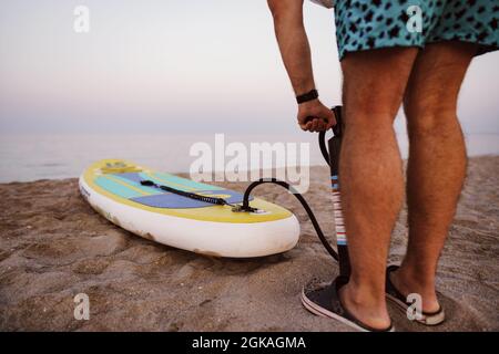 Nahaufnahme des Mannes bereitet sich auf die Paddelsurfen an einem Strand aufblasend supboard Stockfoto